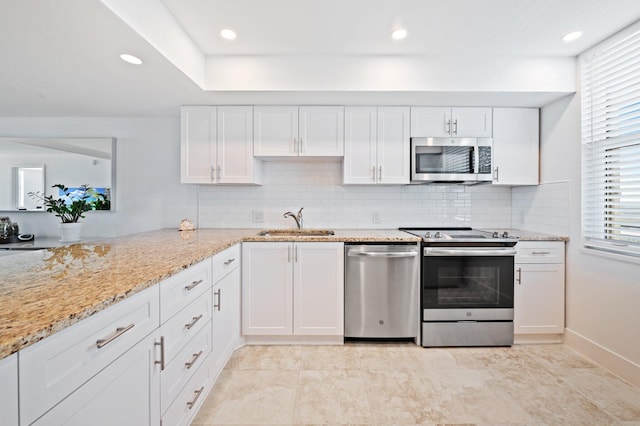 kitchen featuring decorative backsplash, white cabinetry, light stone countertops, sink, and stainless steel appliances