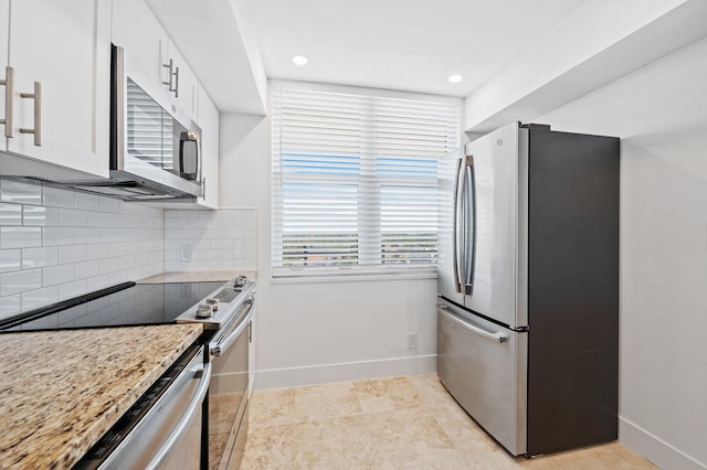 kitchen featuring appliances with stainless steel finishes, decorative backsplash, white cabinetry, and light stone countertops