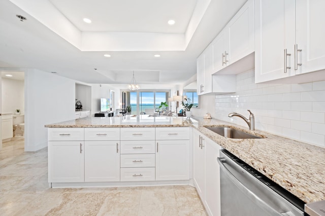 kitchen featuring kitchen peninsula, white cabinetry, sink, and a raised ceiling