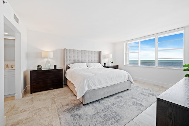 bedroom featuring a water view, connected bathroom, and light tile patterned flooring