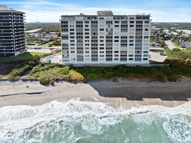 view of building exterior featuring a water view and a beach view