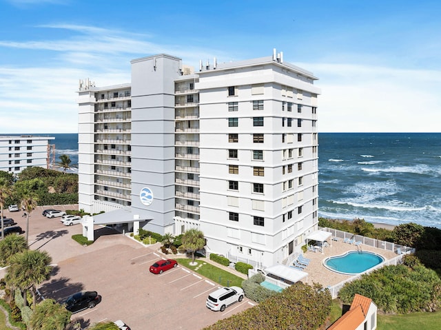 view of building exterior with a water view and a community pool