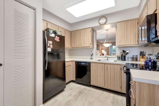 kitchen featuring light brown cabinetry, decorative light fixtures, sink, black appliances, and light hardwood / wood-style flooring