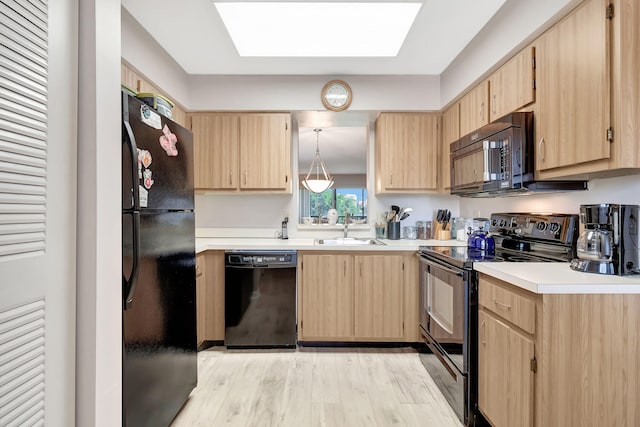 kitchen featuring a skylight, sink, light hardwood / wood-style floors, black appliances, and light brown cabinets