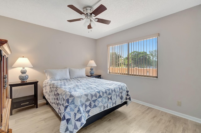 bedroom featuring ceiling fan, light hardwood / wood-style flooring, and a textured ceiling