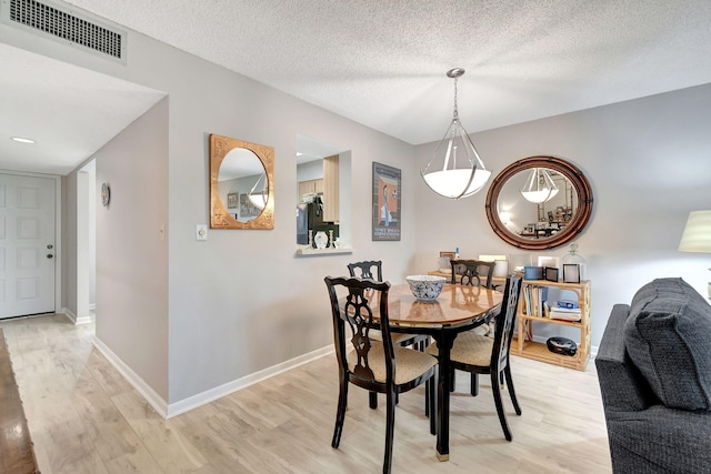 dining room featuring a textured ceiling and light wood-type flooring