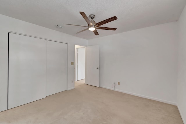 unfurnished bedroom with light carpet, a closet, ceiling fan, and a textured ceiling