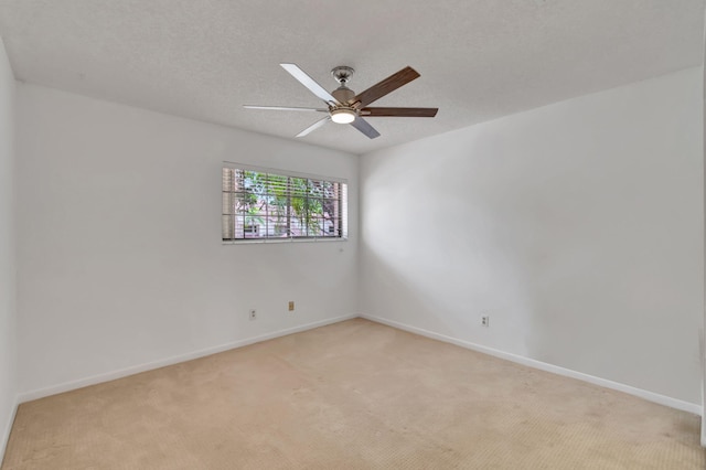 spare room featuring ceiling fan, light colored carpet, and a textured ceiling