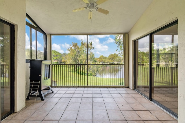 unfurnished sunroom with a healthy amount of sunlight, a water view, and ceiling fan