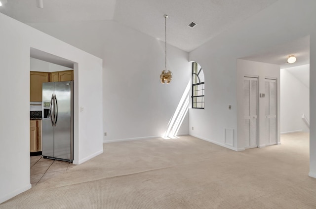 unfurnished living room featuring light carpet and vaulted ceiling