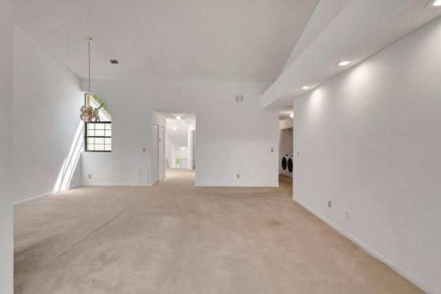 unfurnished living room featuring washer and clothes dryer, light carpet, and a notable chandelier