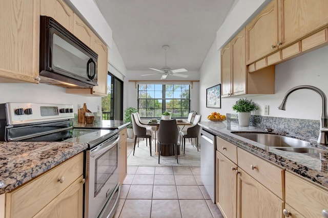 kitchen featuring light tile patterned flooring, vaulted ceiling, light brown cabinets, stainless steel appliances, and sink