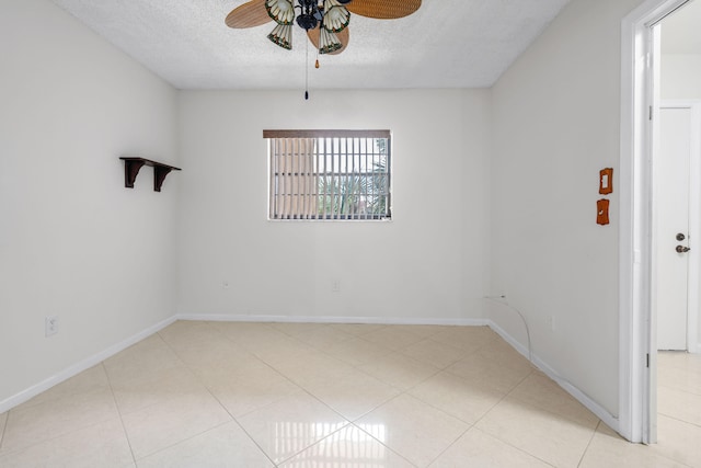 tiled empty room with ceiling fan and a textured ceiling