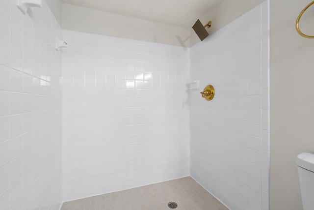 bathroom with a tile shower and toilet