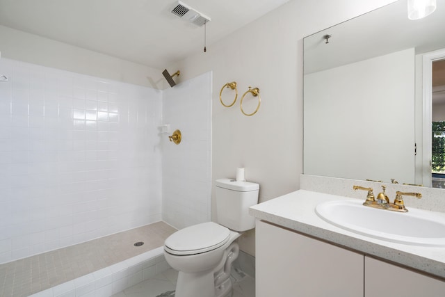 bathroom featuring a tile shower, vanity, and toilet