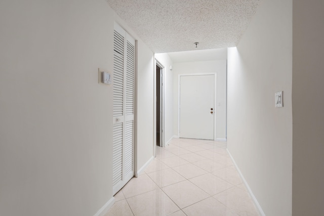 hallway featuring a textured ceiling and light tile patterned flooring