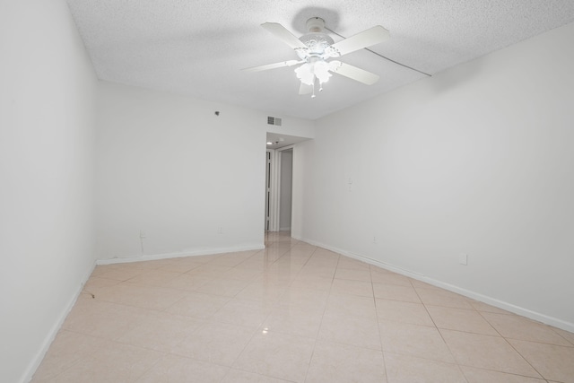 spare room featuring ceiling fan, a textured ceiling, and light tile patterned floors