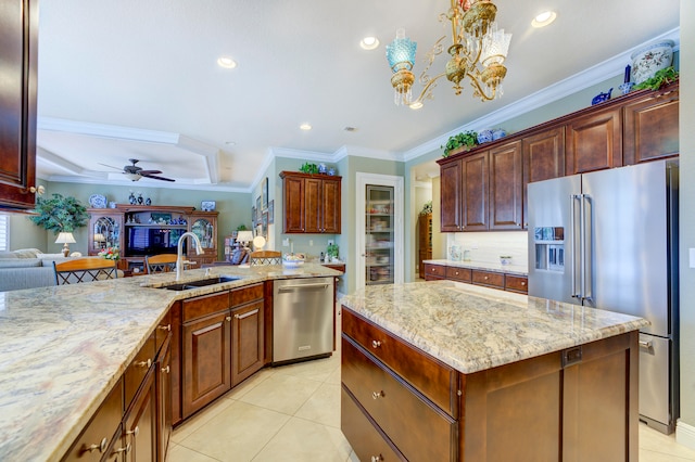 kitchen featuring appliances with stainless steel finishes, an island with sink, pendant lighting, ornamental molding, and sink