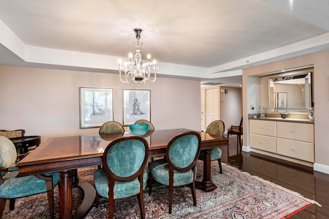 dining space featuring a chandelier, a raised ceiling, and dark wood-type flooring