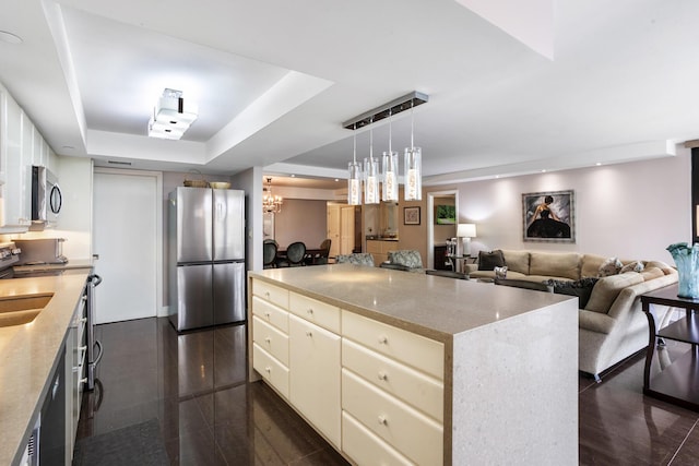 kitchen featuring a center island, an inviting chandelier, a raised ceiling, decorative light fixtures, and stainless steel appliances