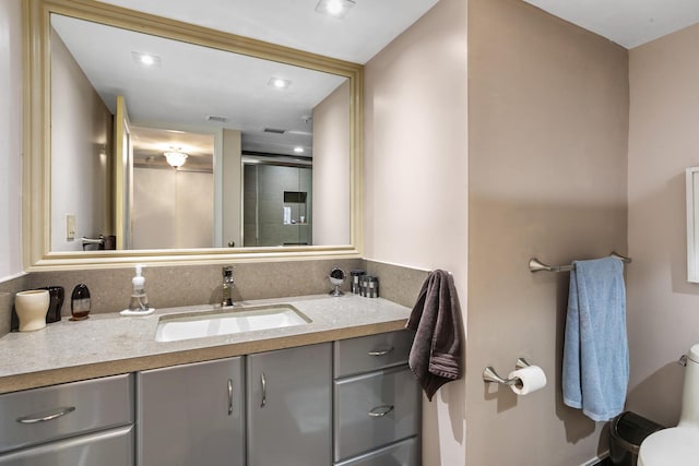 bathroom featuring a shower with door, vanity, and toilet