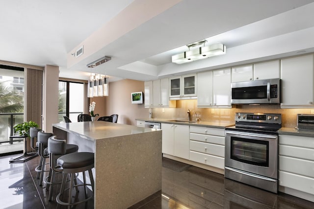 kitchen with a center island, stainless steel appliances, white cabinetry, and sink