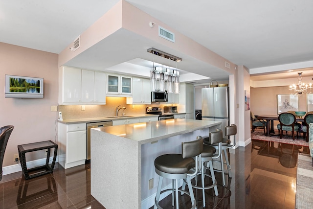 kitchen featuring appliances with stainless steel finishes, backsplash, a kitchen island, sink, and white cabinetry