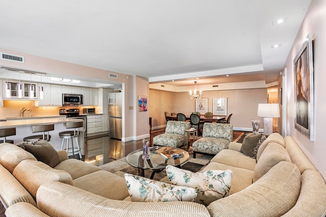 living room featuring hardwood / wood-style flooring, a notable chandelier, and a raised ceiling