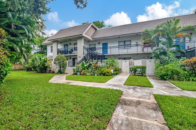 view of property featuring a front yard and a balcony