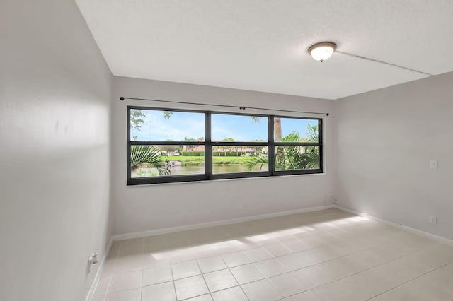 empty room featuring plenty of natural light, light tile patterned floors, and a textured ceiling