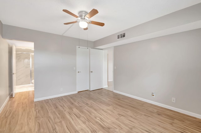 unfurnished bedroom with connected bathroom, light wood-type flooring, and ceiling fan