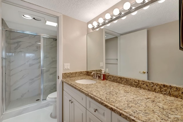 bathroom with walk in shower, vanity, tile patterned floors, toilet, and a textured ceiling