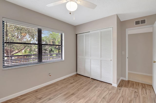 unfurnished bedroom featuring light wood-type flooring, multiple windows, and ceiling fan