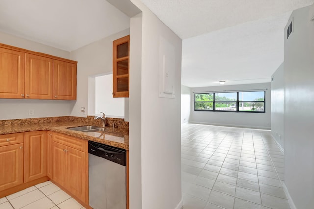 kitchen with light tile patterned flooring, sink, stainless steel dishwasher, and light stone counters