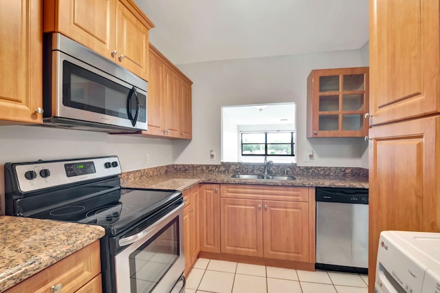 kitchen featuring light tile patterned floors, appliances with stainless steel finishes, sink, and dark stone counters