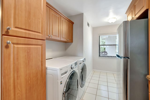 clothes washing area with light tile patterned floors, cabinets, and washer and dryer