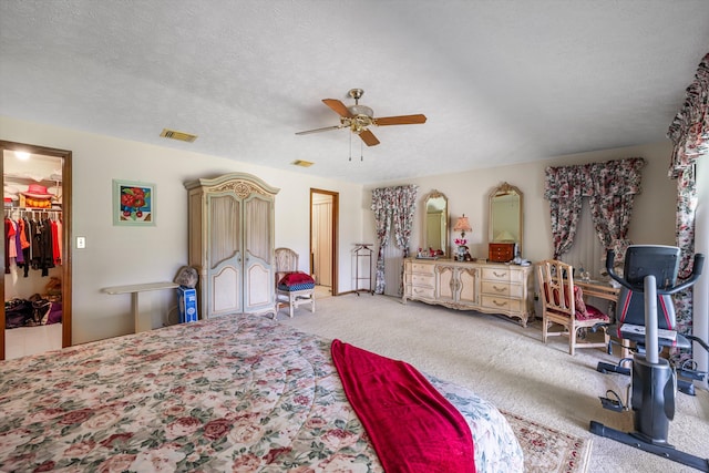 bedroom featuring ceiling fan, a textured ceiling, carpet, a closet, and a spacious closet