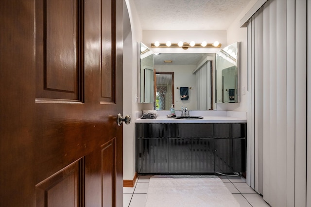 bathroom with tile patterned flooring, a textured ceiling, and vanity