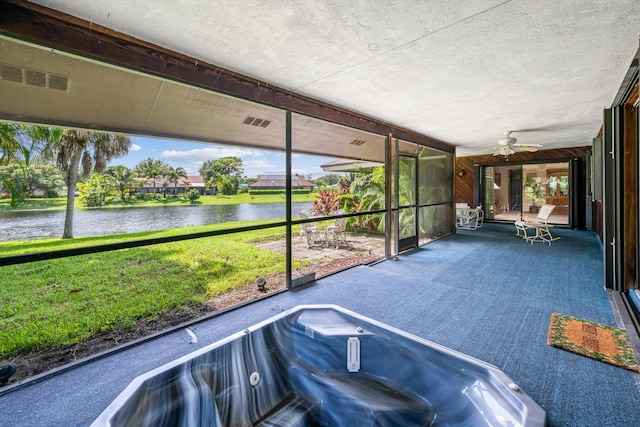 unfurnished sunroom featuring a hot tub, a water view, and ceiling fan