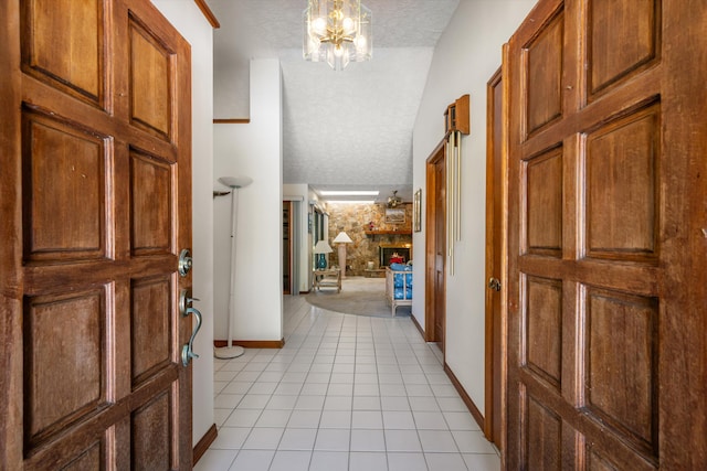 hall featuring a notable chandelier, lofted ceiling, a textured ceiling, and light tile patterned floors