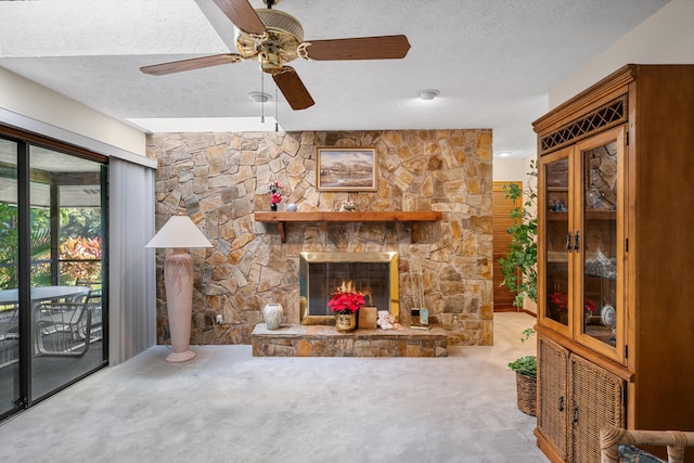 unfurnished living room with a stone fireplace, ornate columns, a textured ceiling, ceiling fan, and carpet