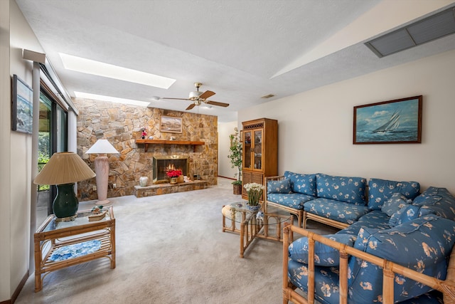 carpeted living room featuring a textured ceiling, a fireplace, ceiling fan, and a skylight