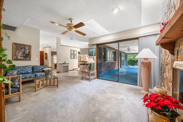 living room with ceiling fan, a skylight, a textured ceiling, and carpet flooring