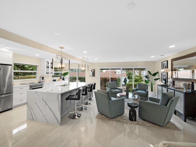 living room featuring sink, plenty of natural light, and an inviting chandelier