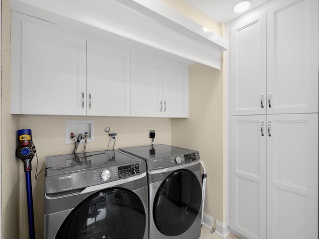 laundry room featuring washer and clothes dryer and cabinets