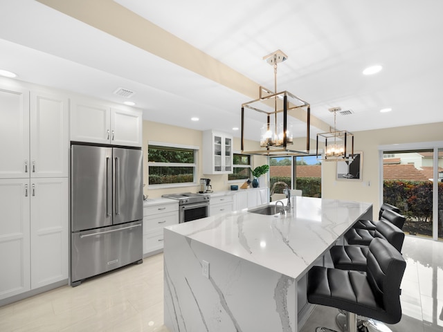 kitchen with light stone countertops, stainless steel appliances, sink, decorative light fixtures, and white cabinetry