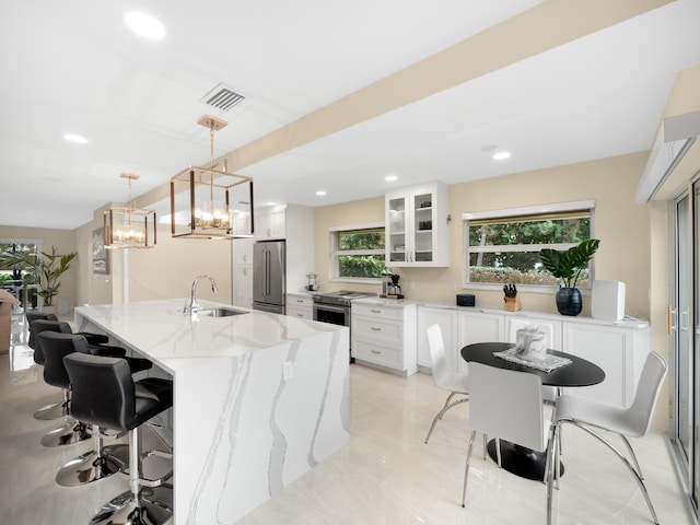 kitchen with white cabinets, sink, a kitchen island, light stone countertops, and high end fridge