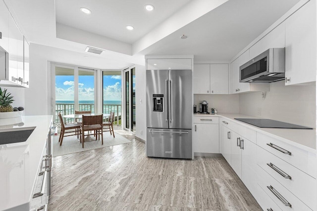 kitchen featuring a water view, white cabinets, stainless steel appliances, and light wood-type flooring