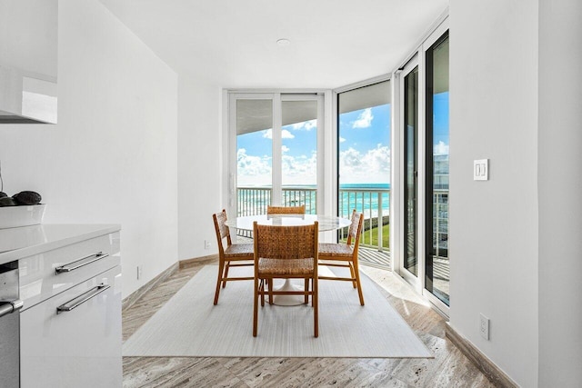 dining space featuring a wall of windows, a water view, and light hardwood / wood-style floors