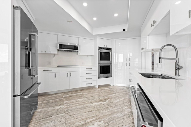 kitchen with white cabinets, stainless steel appliances, sink, and backsplash